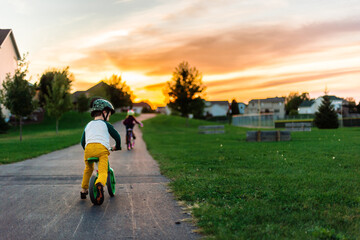 A boy rides a strider bike up a hill at sunset
