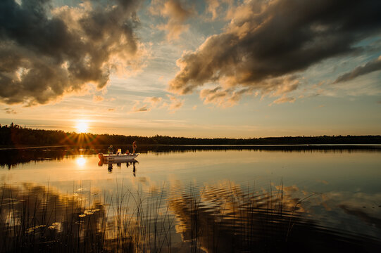 A grandfather, father, and daughter fish on a lake in northern Minnesota at sunset
