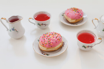 holiday, birthday party composition with colorful pink glazed donuts on white table, flatlay top view