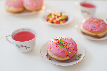 holiday, birthday party composition with colorful pink glazed donuts on white table, flatlay top view