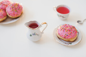 holiday, birthday party composition with colorful pink glazed donuts on white table, flatlay top view