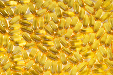 Fish oil capsules with omega 3. Health care concept. Group of yellow tablets. Texture with transparent pills on white background. Backing for text, website, leaflet, layout, flyer, post. Flat lay