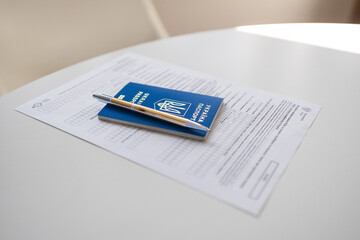 PESEL document, Ukrainian passport and a pen on white table background.