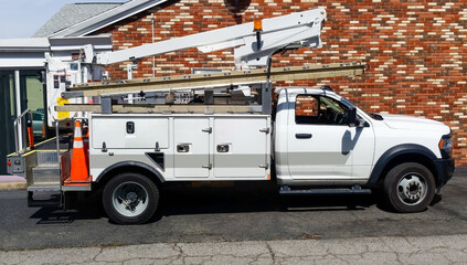Side view of parked communication utility truck in residential neighborhood.