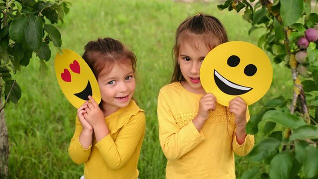Children hide behind cardboard pictures of happy emoticons. World Smile Emoji Day. 