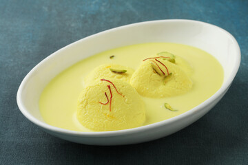 Rasmalai is an Indian dessert sweet with dry fruits and Saffron toppings, served in a bowl . selective focus