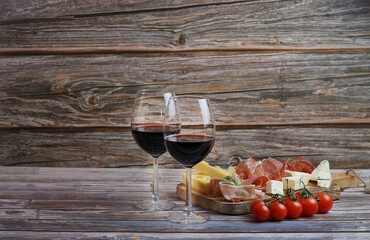 Red wine with charcuterie assortment on the wooden background. Copy space