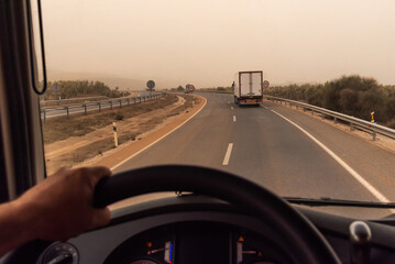 View from the driver's seat of a truck, with a refrigerated trailer driving in front.