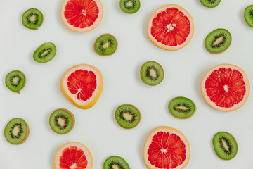 Fruity pattern of kiwi and grapefruit slices on the white background. Top view. Minimal colourful trend style