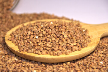 Buckwheat is scattered and in a wooden spatula. Lower angle. Close up.