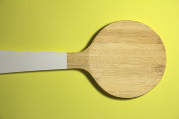 Wooden spoon. In a wooden spoon a white handle. On a yellow background.