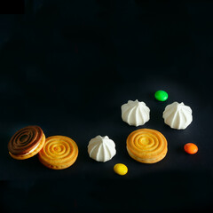 Meringues,cookies and chocolate dragee on a black . Free space for text.