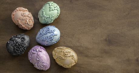 Easter background with unusual Art Nouveau style Easter eggs on the side and space for text on the right. Six embossed carved vintage Easter eggs on a dark wooden background. Art Nouveau Easter eggs. 