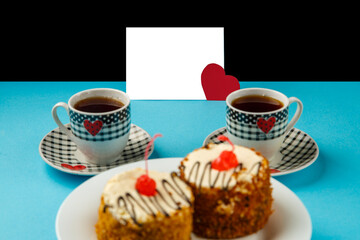 On a blue background, cakes in a plate and two cups of coffee and a card with a declaration of love.