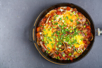 Shakshuka with herbs in a frying pan on a gray background.copy space.