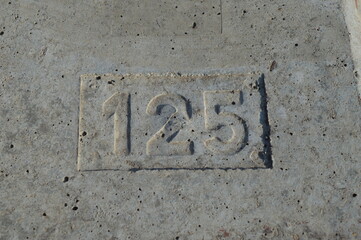 numbers one two five pressed into reinforced concrete