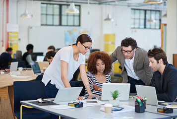 Brainstorming solutions. Cropped shot of business people working on laptops around a table.