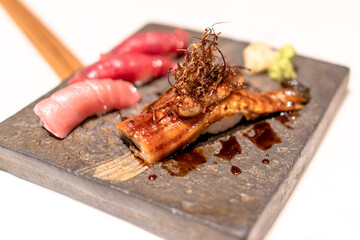 Selective focus. A plate of tuna sushi and unagi nigiri or eel sushi topped with foie gras and...