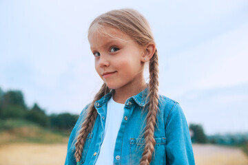Close-up portrait of funny little girl with pigtails outdoor in summer day. Summertime
