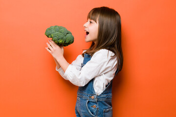 Cute girl eating broccoli in a studio