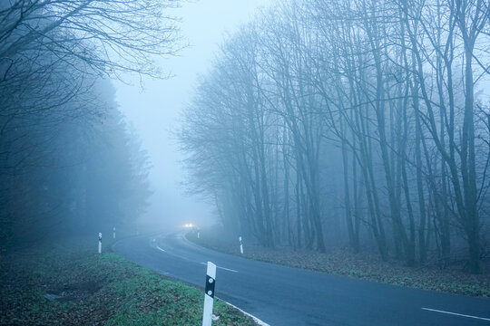 car driving on dark and foggy forest road