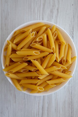 Homemade Raw Dry Penne Pasta in a White Bowl, top view. Flat lay, overhead, from above.