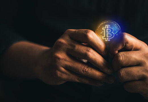cryptocurrency crisis from ukraine war, businessman hand holding gold bitcoin - virtual Btc neon blue and yellow colors that convey to ukraine flag