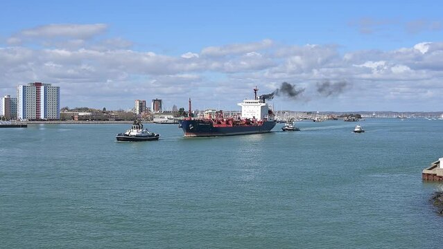  A chemical, oil tanker called Cumbrian Fisher with tug boats departing Portsmouth Harbour.