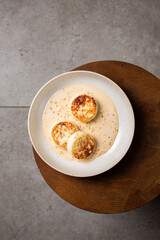 Cottage cheese pancakes or syrniki with caramel sauce and nuts. Concept dark and moody healthy breakfast. Macro and selective focus image.
