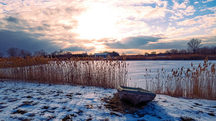Heavenly winter clouds above a abandoned rural boat on lake