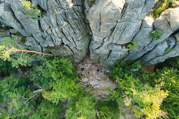 Aerial view of bright landscape with green forest trees and big rocky boulders between dense woods in summer. Beautiful scenery of wild woodland