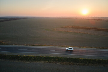 Aerial view of intercity road with blurred fast driving car at sunset. Top view from drone of...