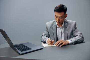 manager sitting at a desk in front of a laptop work writing in a notebook executive