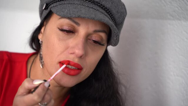 Woman paints lips with red lipstick