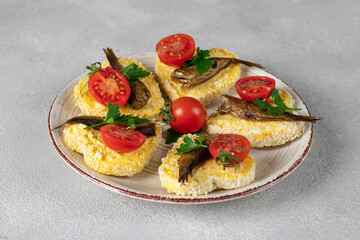 Sandwiches with sprats, cheese, egg and cherry tomatoes in the form of hearts on gray background, Idea for Valentine's Day