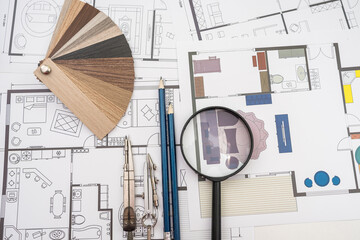 working at office desk with house blueprints for new project and color sampler drawing instruments