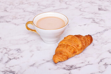 
Coffee cup and sweet vanilla croissant on white table
