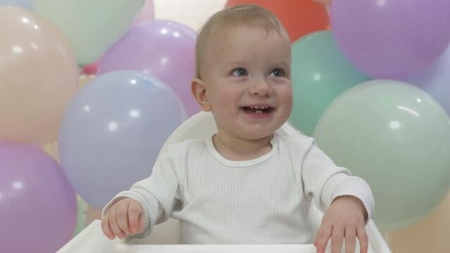 Father giving a toy to happy child at birthday party, one year old baby boy celebrating his first birthday, cute kid smiling against colorful balloons at home. High quality 4k footage