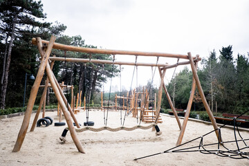 Playground in the forest, colorful children's toys in the park, swing, slide, wooden toys. Selective focus.