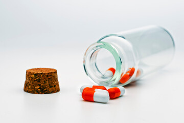 glass bottle with colored pills inside on a white background