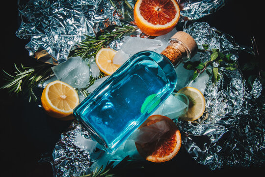 bottle of gin with lemon and grapefruit, rosemary, mint. Foil background