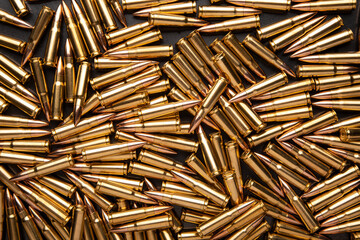 A pile of ammunition for weapons. Cartridges for machine guns and carbines. Background from new shiny cartridges. - obrazy, fototapety, plakaty