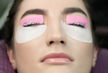 Master applies care perm cream to eyelashes. Close-up of beauty model's face during lash lift...