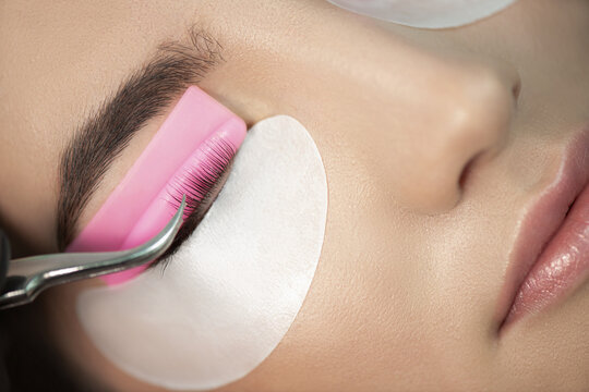 Master glues eyelashes to pink lash roller. Close-up of beauty model's face during lash lift laminating botox procedure. Eyelash Care Treatment: eyelash lifting and curling, lash lamination 