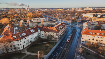 Fototapeta na wymiar Marynarki Polskiej Street with tram tracks and a running tram. In the background the stadium. Winter morning. View from the drone.