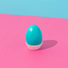 Cyan Easter egg against bold pink and cyan background. Minimal Easter concept. Fun food idea.