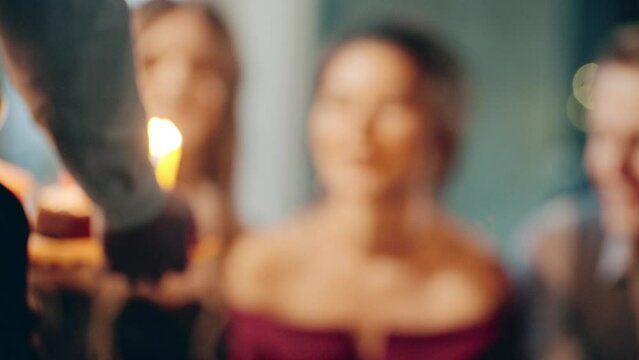 Close-up portrait of smiling asian girl and friends making surprise and taking out birthday cake with candles. Young woman blowing out fire on candles and making wish at party or celebration.