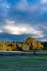 dramatic skies over grass and autumn trees