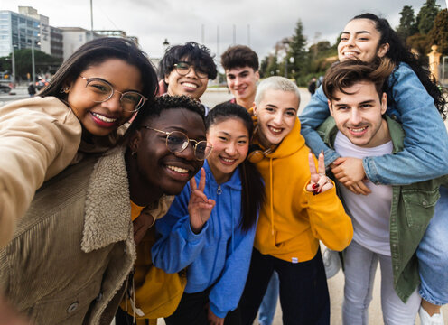 Portrait selfie group of young multiethnic students outdoors - Happy diverse friends having fun together - Focus on african american woman face on the left