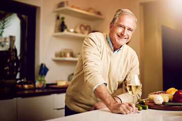 Wine is my favourite entree. Shot of a senior man enjoying a glass of wine while preparing dinner in his kitchen.